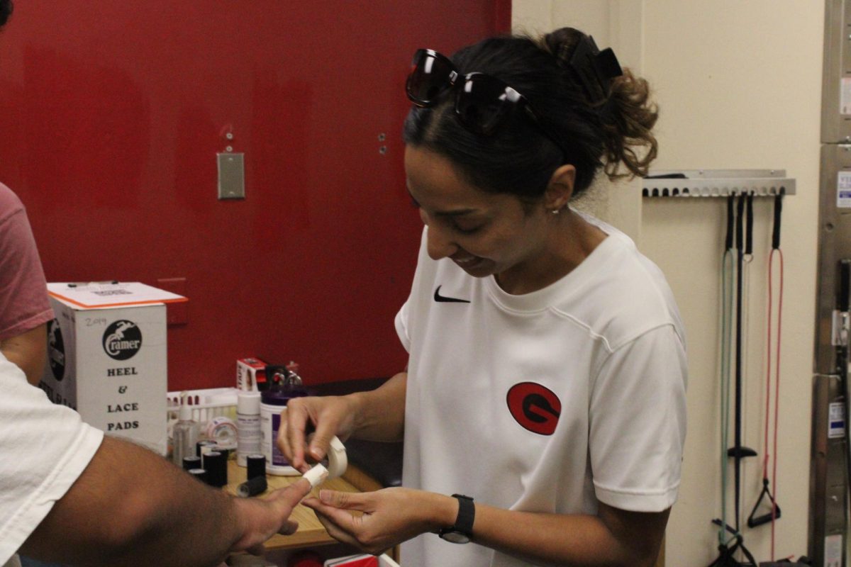 Athletic trainer Gagan Cheema bandages an injured student鈥檚 finger.